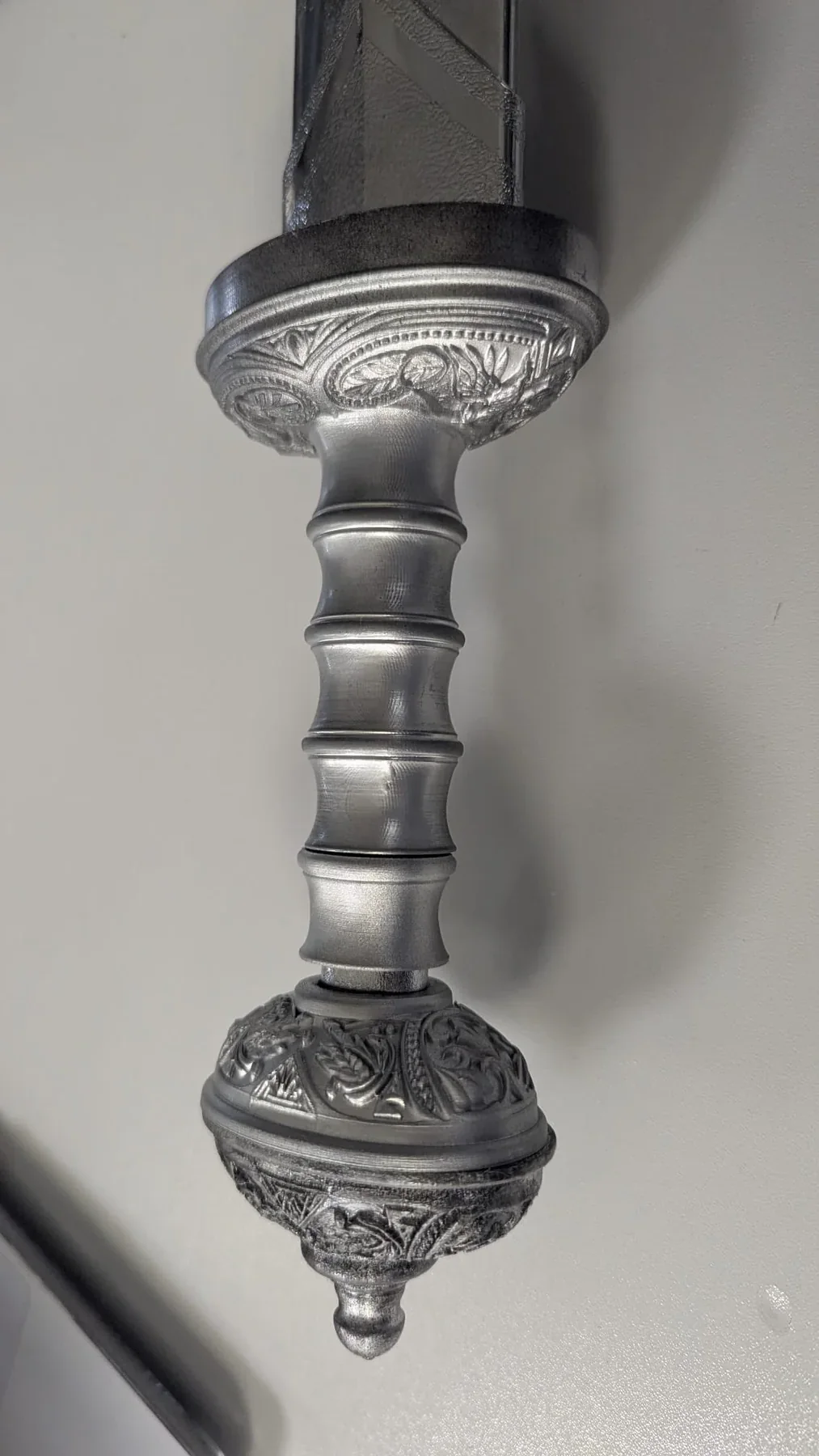 Empuñadura ornamental con relieves y acabado metálico